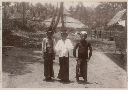 Three children standing, with buildings in background