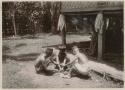 Two men and a boy sitting and working with wood