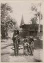 Woman with two children, house in background