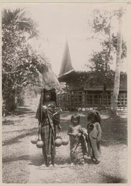 Woman with two children, house in background