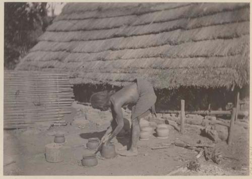 Person making pottery in front of building