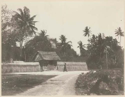 Person walking on road next to a structure