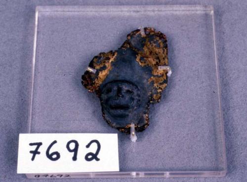 Fragment of gold object, human face