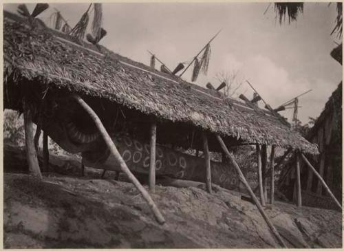 Large wooden object under a thatched structure