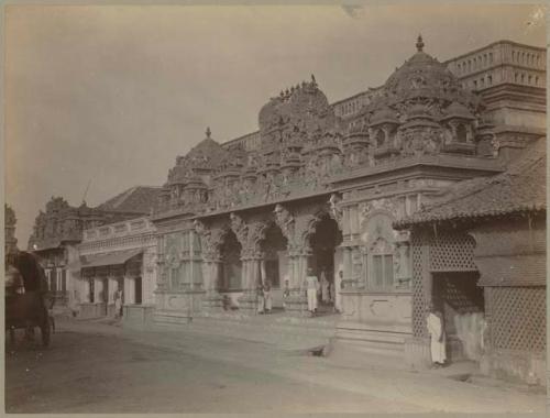 People sit outside building with carved domes