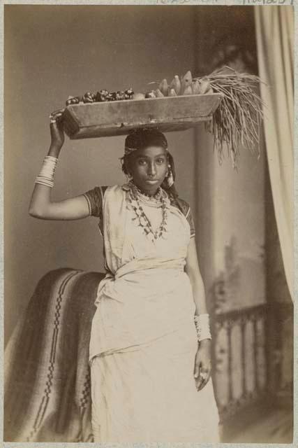 Portrait of woman in sari, holding tray on head