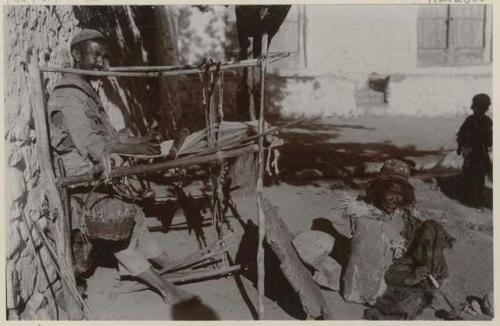 Man at loom with wife spinning