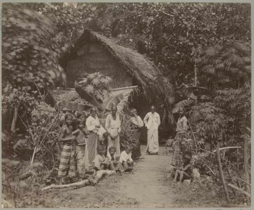 Women and children in front of hut in jungle