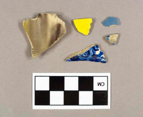 One blue hand painted pearlware body sherd; one flow blue pearlware body sherd; one blue annular banded pearlware body sherd; one yellow with red transfer print pearlware body sherd; one purple and green clouded Wheldon ware rim sherd