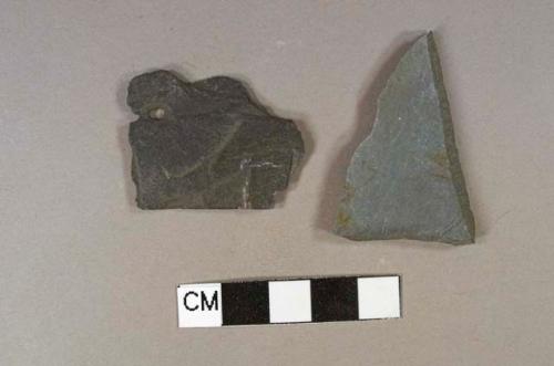 Two pieces of gray slate; one has a hole and is likely a roof tile