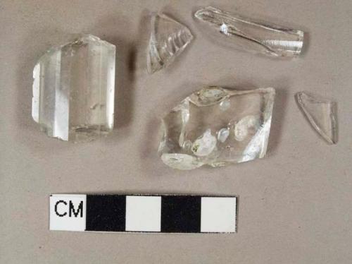 Four colorless bottle glass fragments; one faceted colorless glass chandelier or candlestick pendant fragment