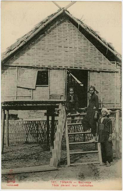 Three people in front of a house