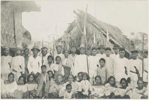 Group, some with spears, in front of buildings