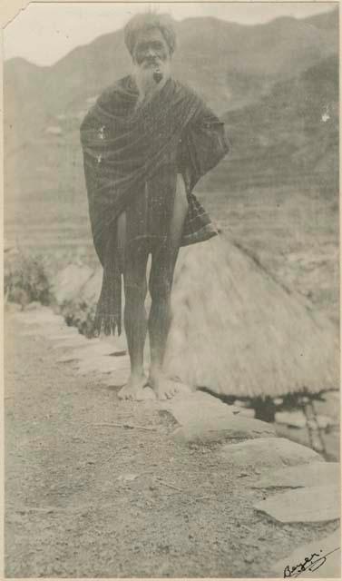 Lañ-bai-'yan wearing a blanket, standing