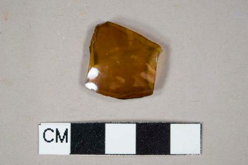 Amber vessel glass body fragment, likely shoulder fragment