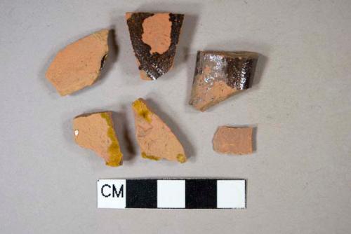 One unglazed redware body sherd; one lead glazed redware handle sherd; four lead glazed redware body sherds, two crossmend