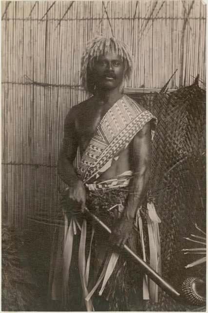 Fijian man in a studio-staged scene, holding a club