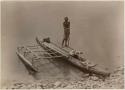 Man standing in outrigger canoe at the shore