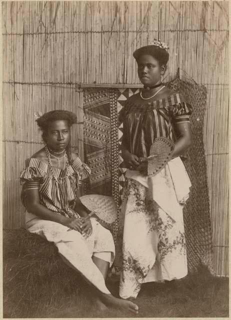 Staged portrait of two women holding fans