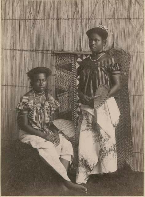 Staged portrait of two women holding fans