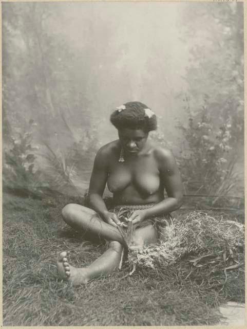 Studio portrait of woman plaiting mat