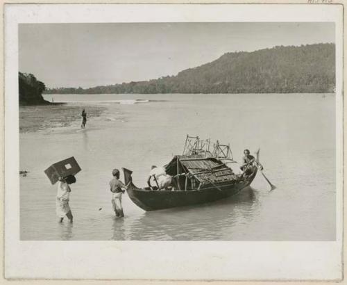 Two men on boat and men in water near boat