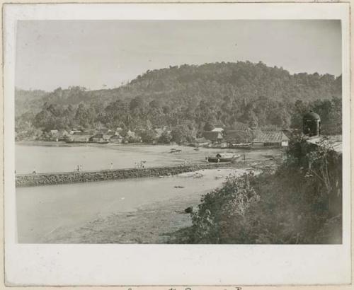 Shoreline with buildings and people walking on jetty