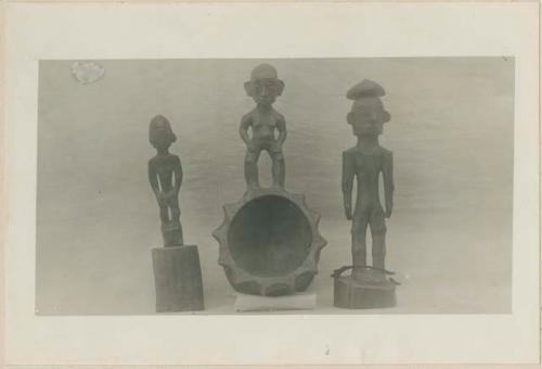 Front view of carved wooden ladle and two small wooden images