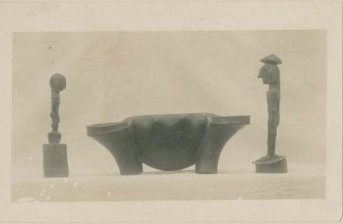 Side view of carved woodem bowl and of two wooden images