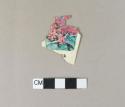 Polychrome printed plastic fragment; printed with flowers and text, likely a plant label card