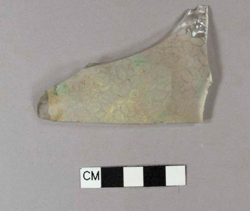 Colorless curved glass fragment with molded, frosted floral decoration, with paint on the surface