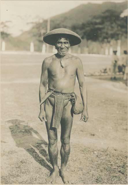 Bontoc Igorot man wearing sun hat and carrying in his girdle a head-axe and pouch pocket