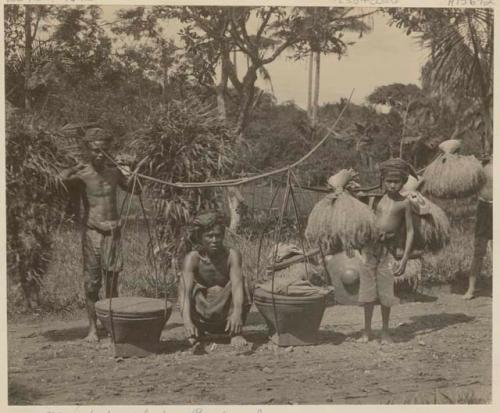 Men and boy carrying various goods on their shoulders