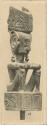 Wood sculpture of a divinity seated on a cubic pedestal, with arms crossed, legs folded and elbows on knees