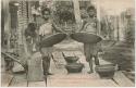 Women winnowing rice on porch