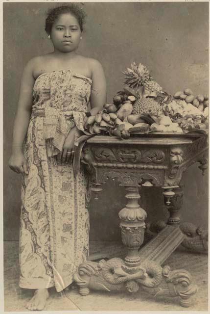 Studio portait of woman standing next to table with fruit