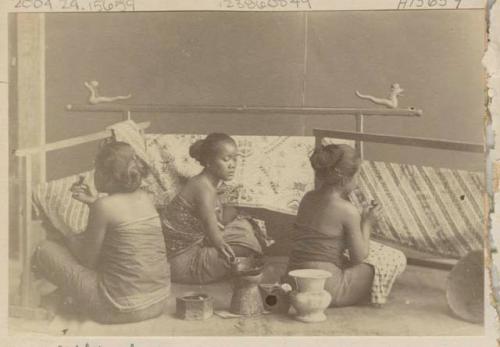 Three girls applying wax to fabric before dyeing