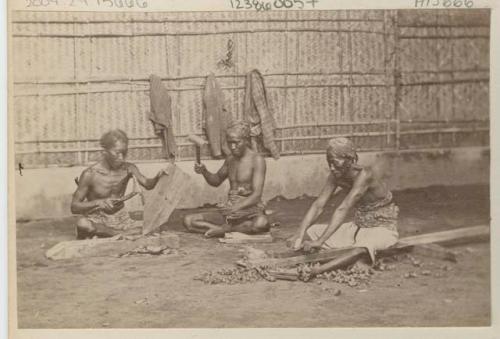 Three men using hammers and other tools