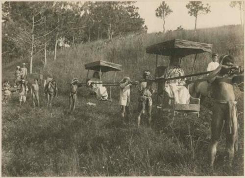 Igorot men carrying people and loads on the trail