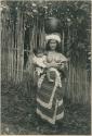 Igorot woman holding baby and balancing water container on her head