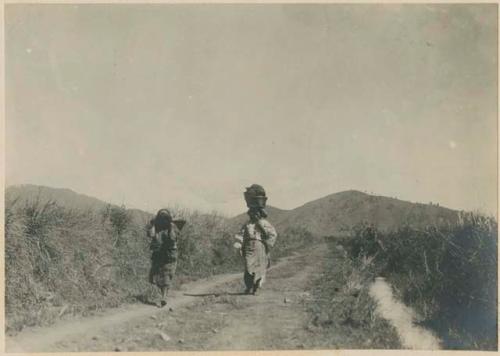 Ilocano woman with an Igorot woman carrying a load of goods for her