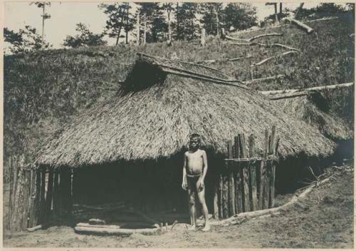 Igorot boy in front of house
