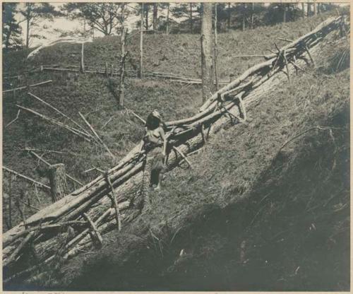 Igorot woman next to fence enclosing a clearing