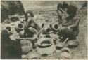 Igorot women smoothing sun-dried pots by rubbing with stone