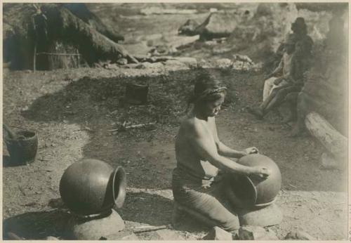 Igorot women smoothing sun-dried pots by rubbing with stone