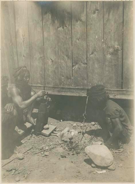 Igorot men making metal pipes