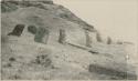 Man standing in front of Moai on hillside