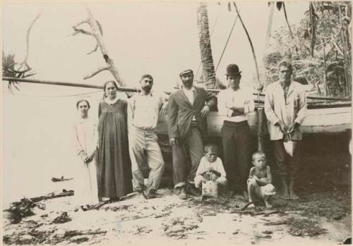 Group of men, women and children in front of a boat