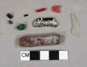 Plastic fragments, 1 white, 1 colorless, 2 dark brown, 2 red, 2 green, 1 medium brown rectangular bar, 1 white and black ChapStick container fragment