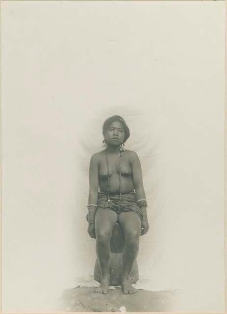 Young Kalinga woman posed seated on a rice mortar